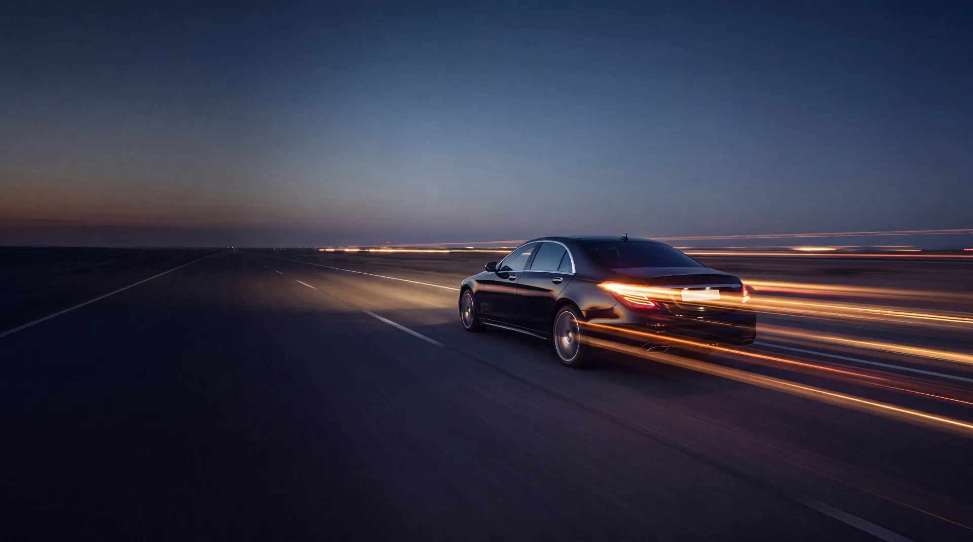 Black Mercedes S-Class chauffeur car driving at dusk with motion light trails — Prestige Travel Group Milton Keynes