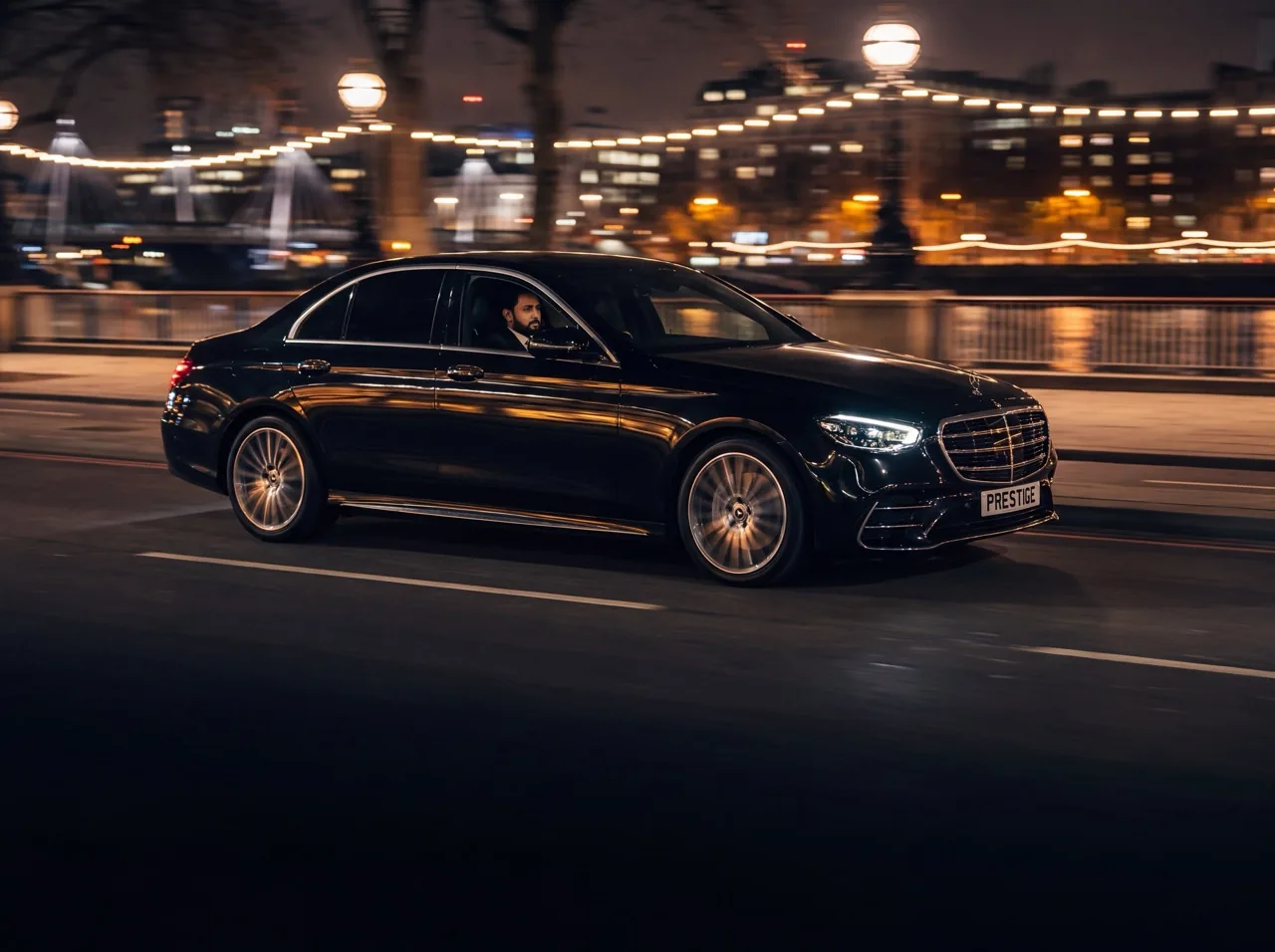 Chauffeur waiting beside a black Mercedes E-Class on a London street